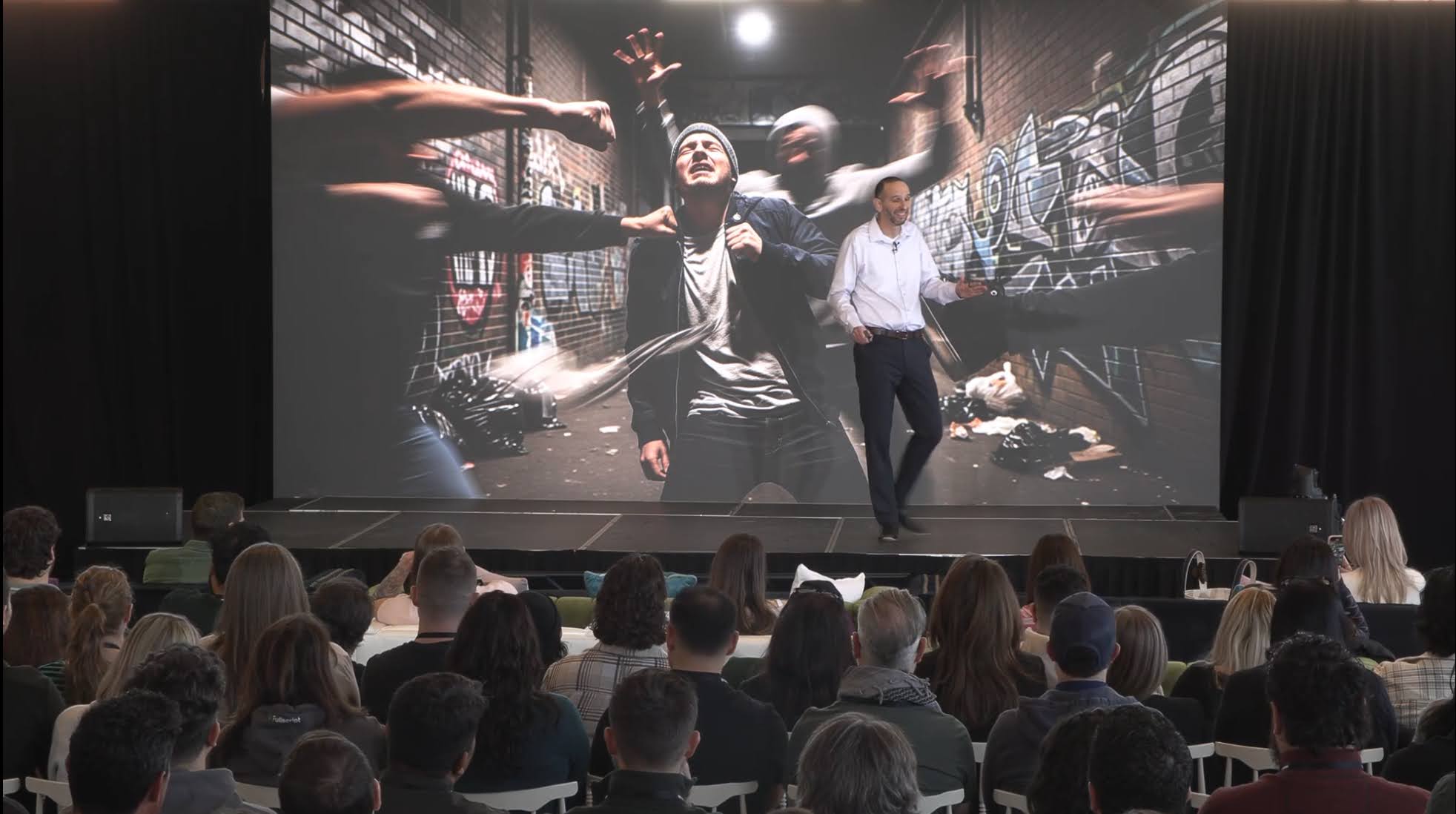 Ziv Pollak on stage with action slide